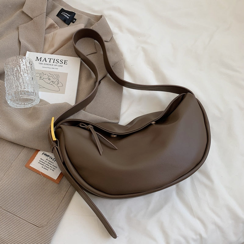 Braune Lederhandtasche mit Schulterriemen auf beigem Blazer, stilvoll und elegant.