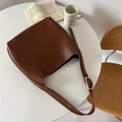 Braune Ledertasche auf Tisch, neben Buch und Tasse, modisches Accessoire, Damenhandtasche.