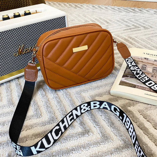 Braune Umhängetasche aus Leder mit gestepptem Design und verstellbarem Schultergurt.