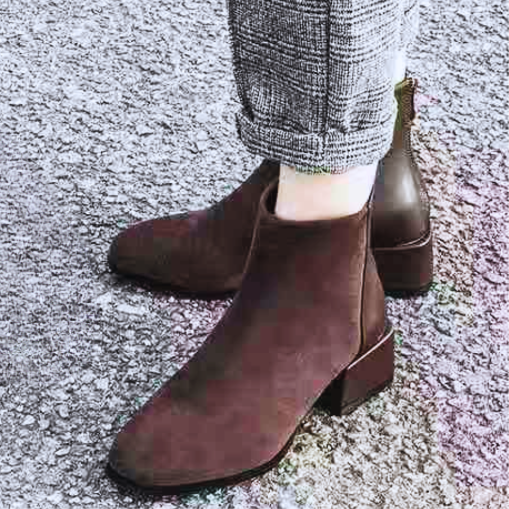 Braune Damen-Stiefeletten aus Leder, elegantes Design, Herbstmode, auf Asphalt getragen.