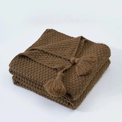 Braune Strickdecke mit Quasten, weiches Baumwollmaterial, gemütliche Wohnaccessoires.