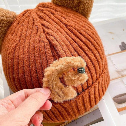Braune Strickmütze mit Bärenohren, handgehalten, weiches Material, modisches Accessoire.
