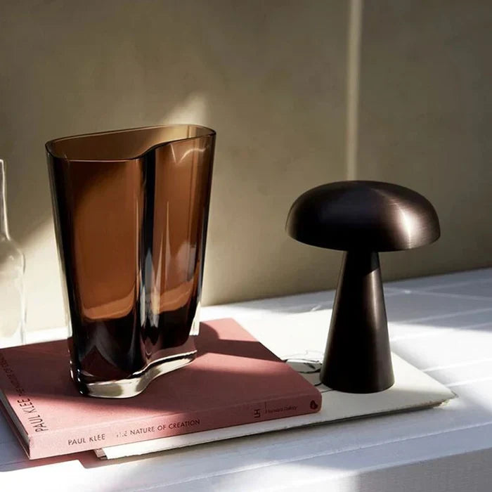 Braune Glasvase und schwarze Pilzlampe auf Tisch, moderne Wohnkultur, stilvolles Design.