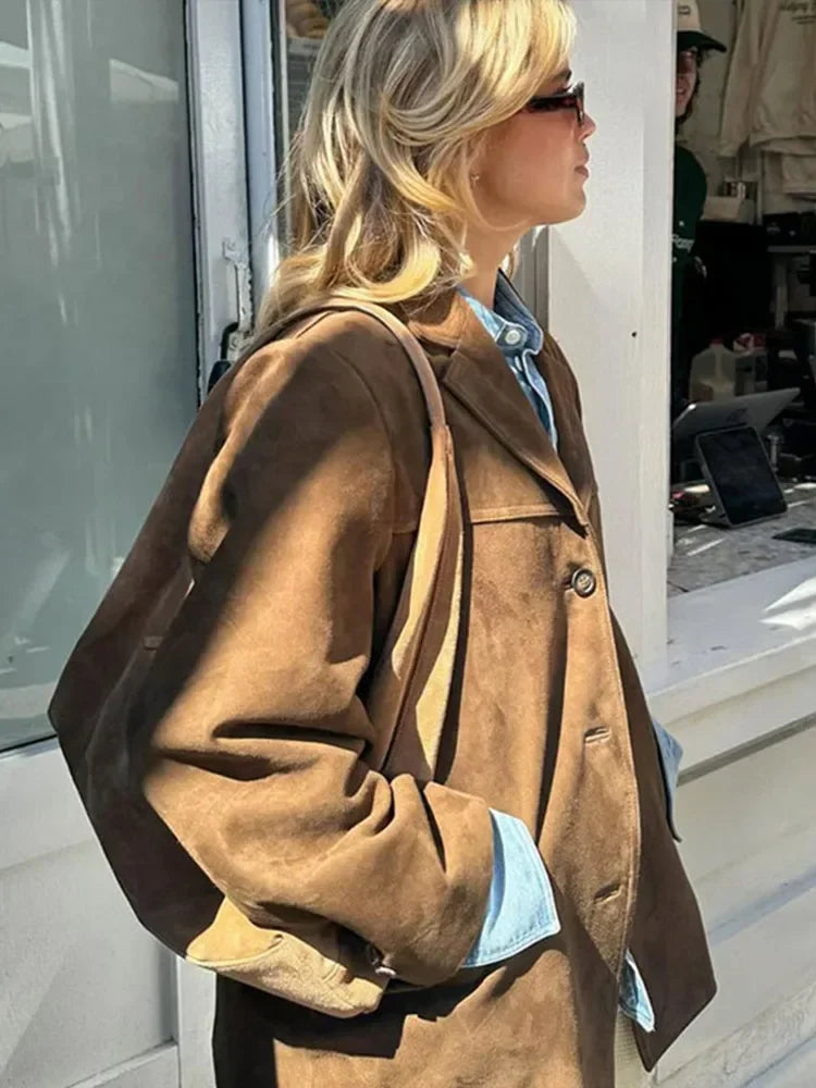 Frau in brauner Wildlederjacke, Sonnenbrille, blauer Hemd, modisch, urbaner Stil.