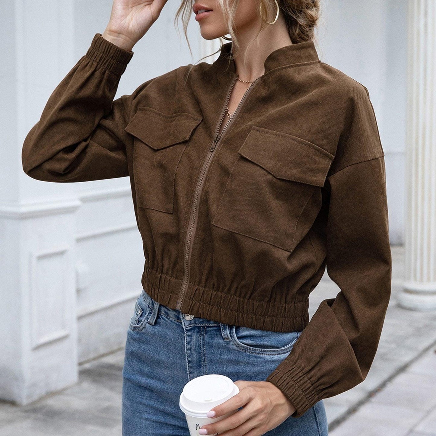 Frau in brauner Wildlederjacke, lässig, modisch, Herbstmode, Kaffeebecher, Jeans.