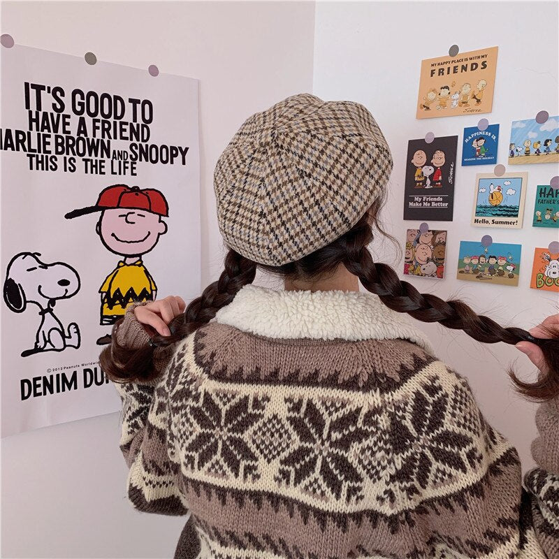 Mädchen mit Zöpfen, karierter Baskenmütze, Strickpullover, Charlie Brown Poster im Hintergrund.