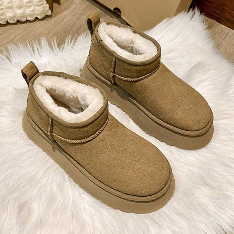 Braune Damen-Winterstiefel aus Wildleder mit Fellfutter auf weißem Teppich.