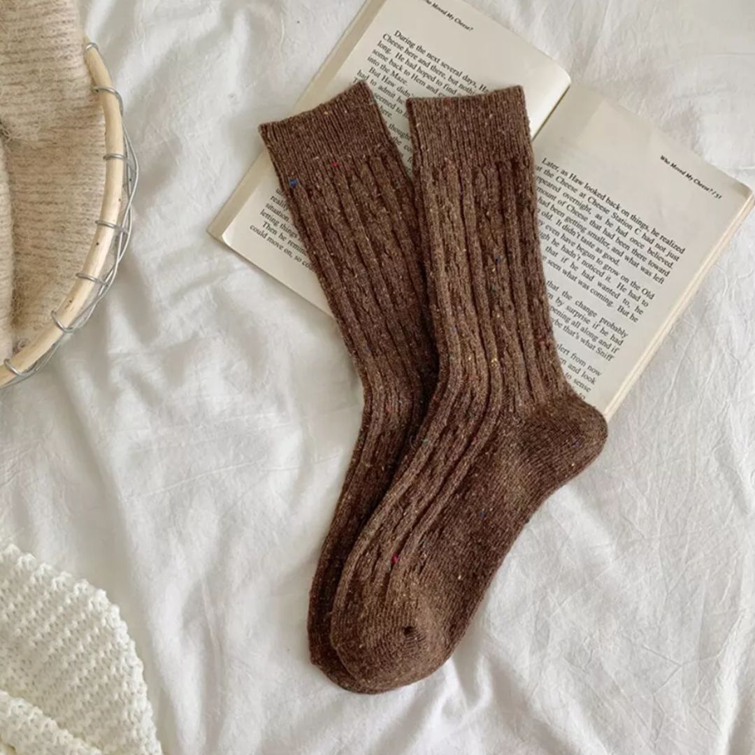 Braune Wollsocken auf offenem Buch, gemütlich, warm, Strickdesign, Herbstmode Accessoire.