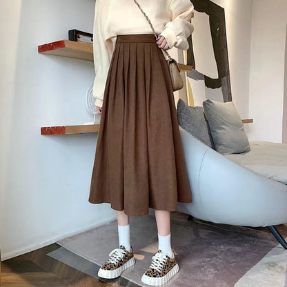 Damenmode: Brauner Faltenrock, cremefarbener Pullover, Leoparden-Sneaker, Wohnzimmer-Hintergrund.
