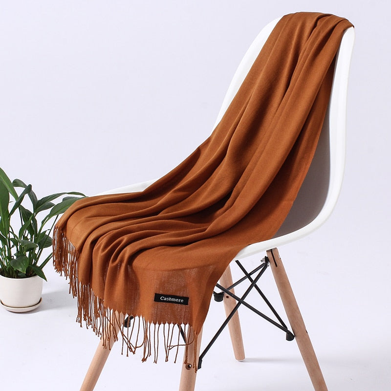 Brauner Kaschmirschal auf weißem Stuhl, weiches Material, modisches Accessoire, Wohnzimmer.