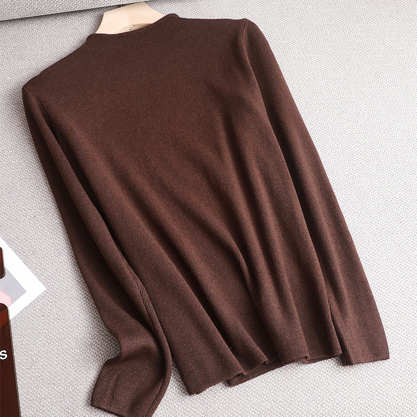 Brauner Strickpullover aus Wolle, langärmelig, auf Kleiderbügel, modisch, Herbstbekleidung.