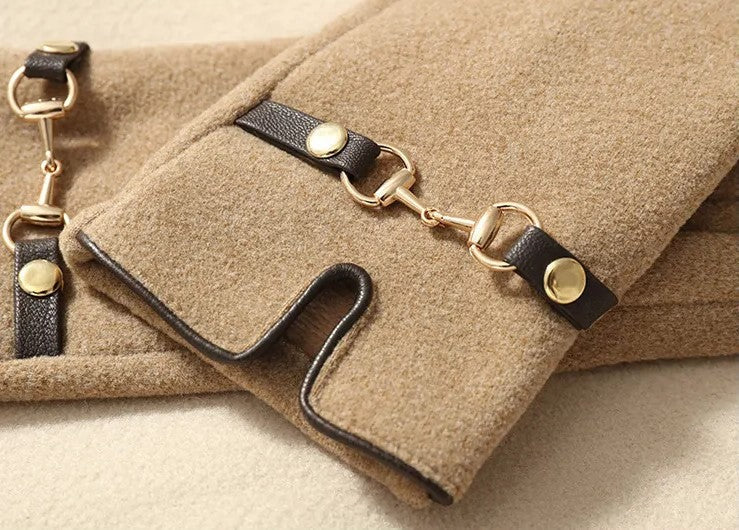 Beige Wollmantel mit schwarzen Lederriemen und goldenen Schnallen, elegantes Damenmode-Accessoire.