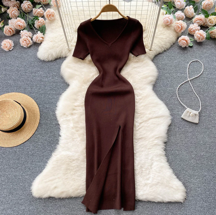 Braunes Strickkleid mit V-Ausschnitt, Kurzarm, Schlitz, auf weißem Fellteppich, elegantes Design.