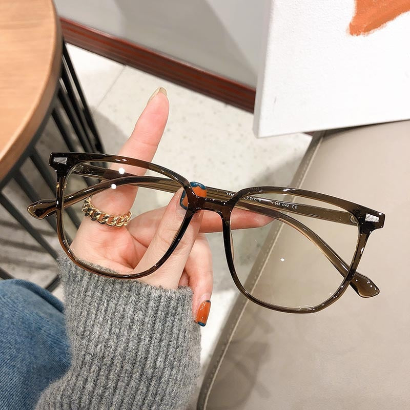 Braune, eckige Brille aus Kunststoff, modisch, auf grauem Hintergrund gehalten.