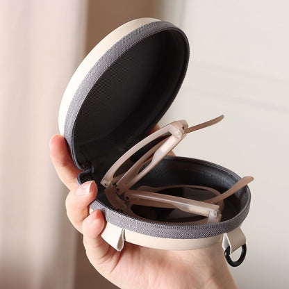 Geöffnete Brillenetui aus Stoff, beige und grau, mit Brille, handgehalten.