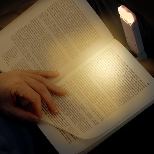 Person liest Buch mit LED-Leselampe, warmes Licht, tragbar, ideal für Nachtlesen.