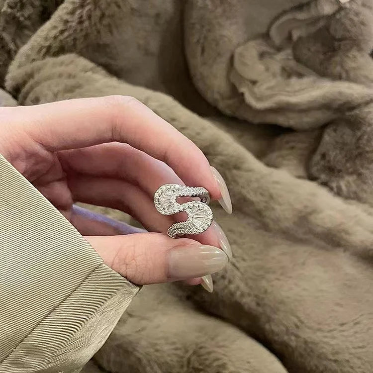 Hand hält silbernen Buchstabenanhänger "S" mit Strasssteinen, eleganter Schmuck, Nahaufnahme.