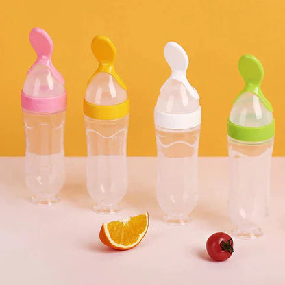 Vier bunte Babyflaschen mit Löffelaufsatz vor gelbem Hintergrund, transparentes Design.