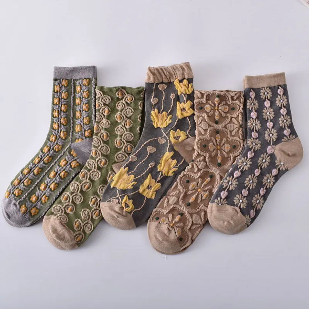Fünf Paar bunte, bestickte Socken mit Blumenmuster auf weißem Hintergrund.