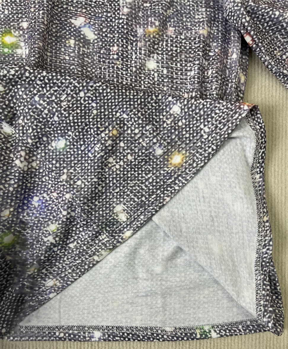 Graues, gepunktetes Damenkleid aus Baumwolle mit buntem Muster, Nahaufnahme des Stoffes.