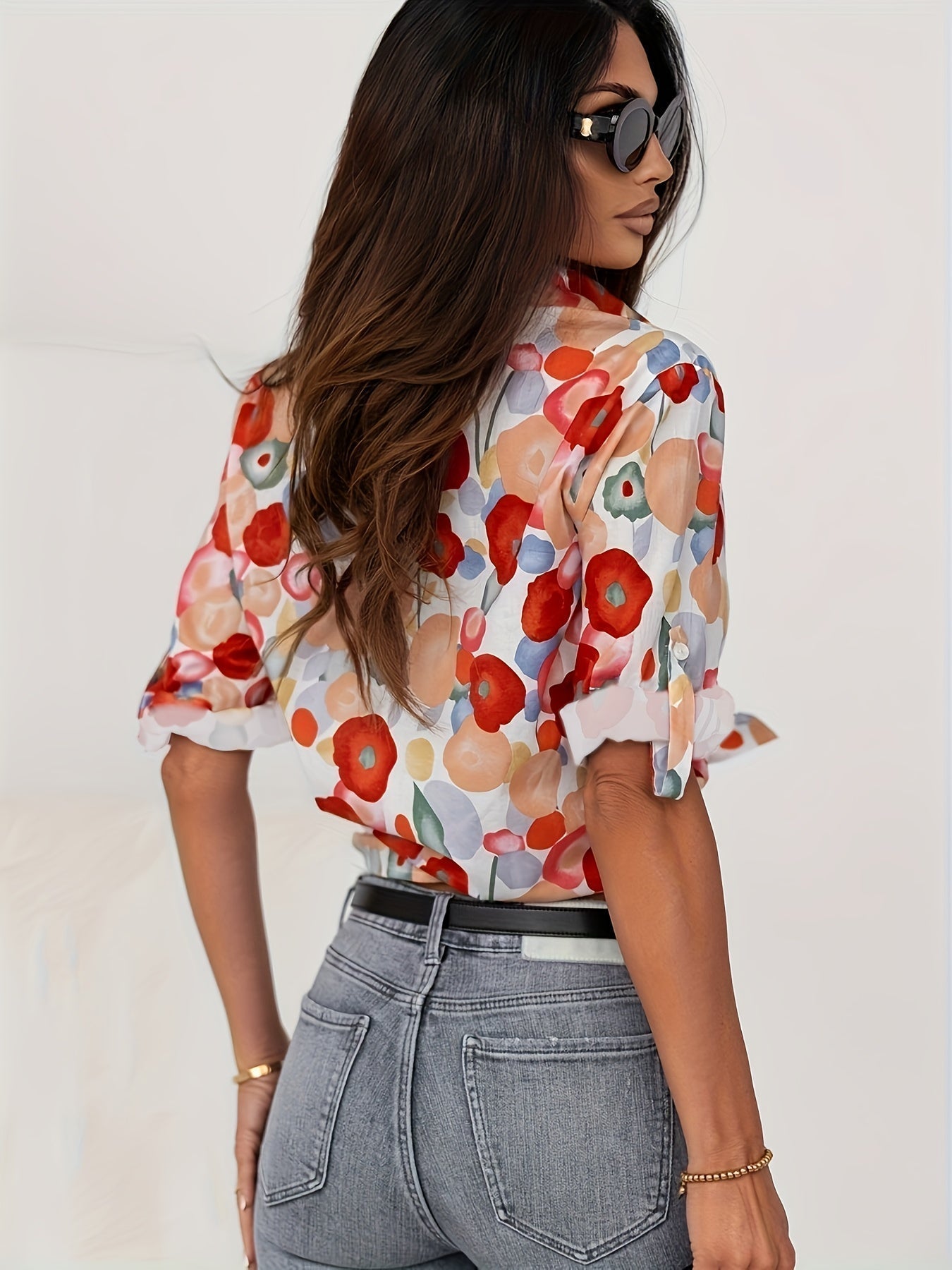 Frau in bunter Bluse mit Blumenmuster, Sonnenbrille, Jeans; modische Damenbekleidung.