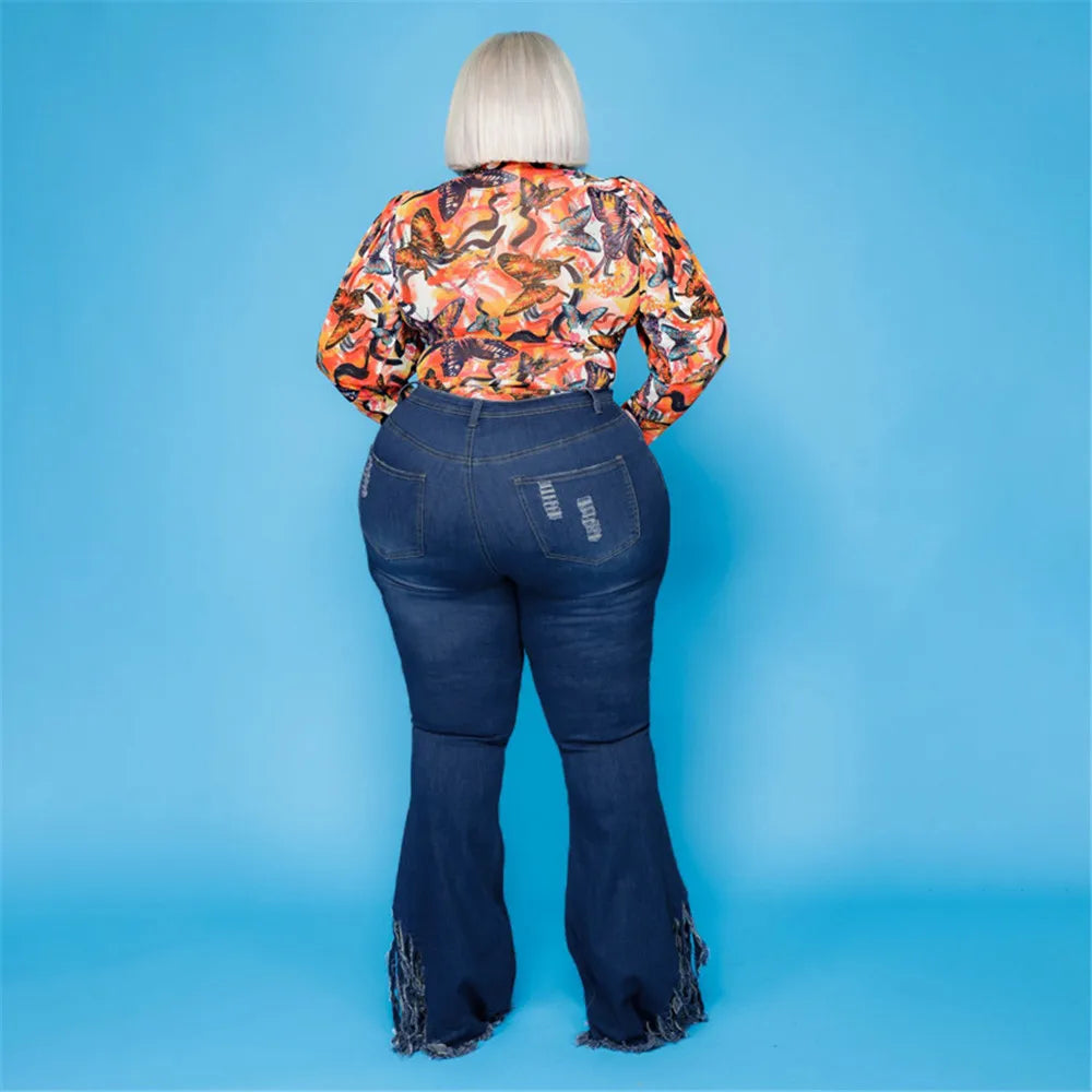 Frau in bunter Bluse und Schlagjeans vor blauem Hintergrund, Mode für große Größen.