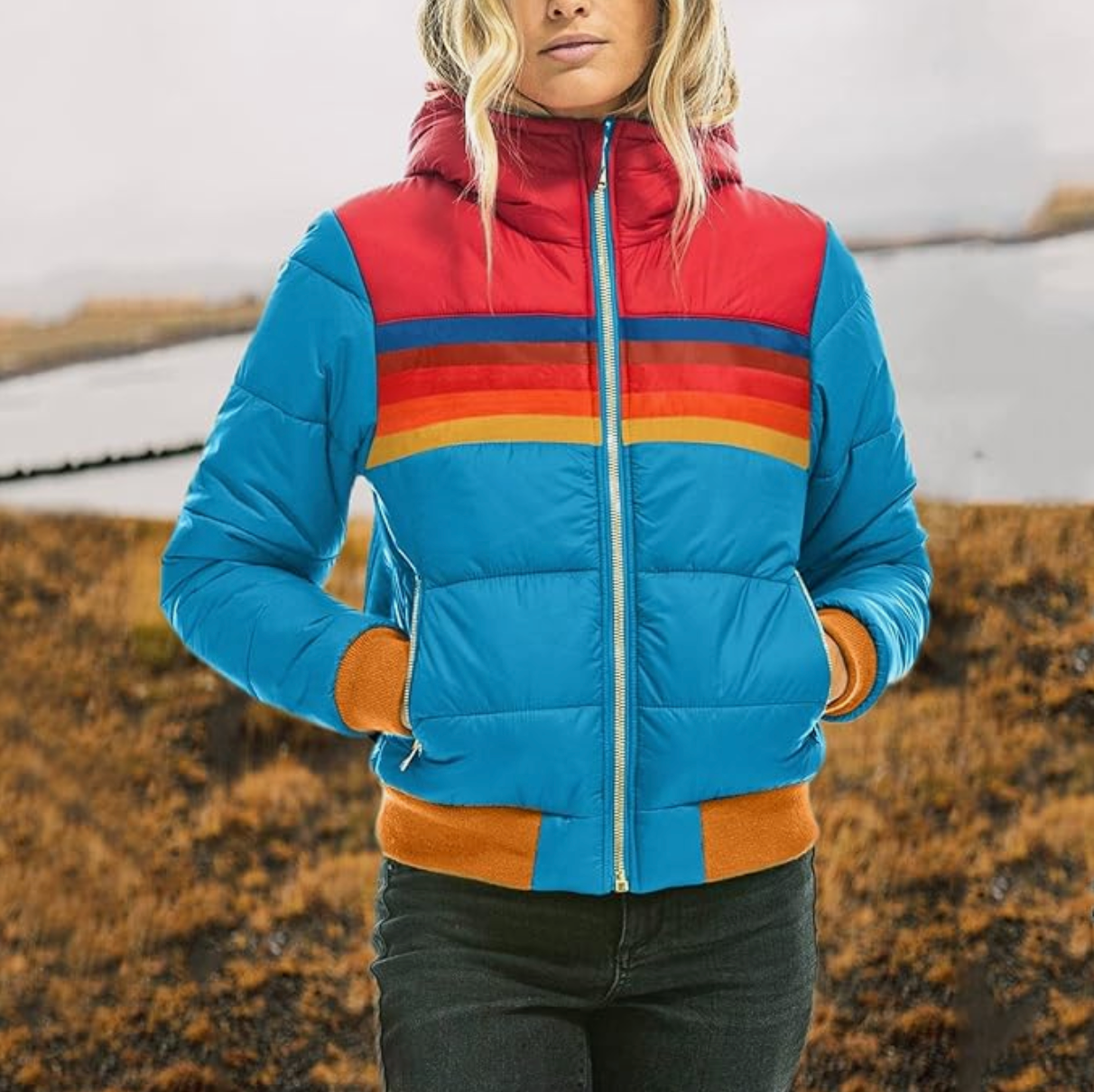 Frau in bunter Daunenjacke, blau mit roten und orange Streifen, Outdoor-Herbstmode.