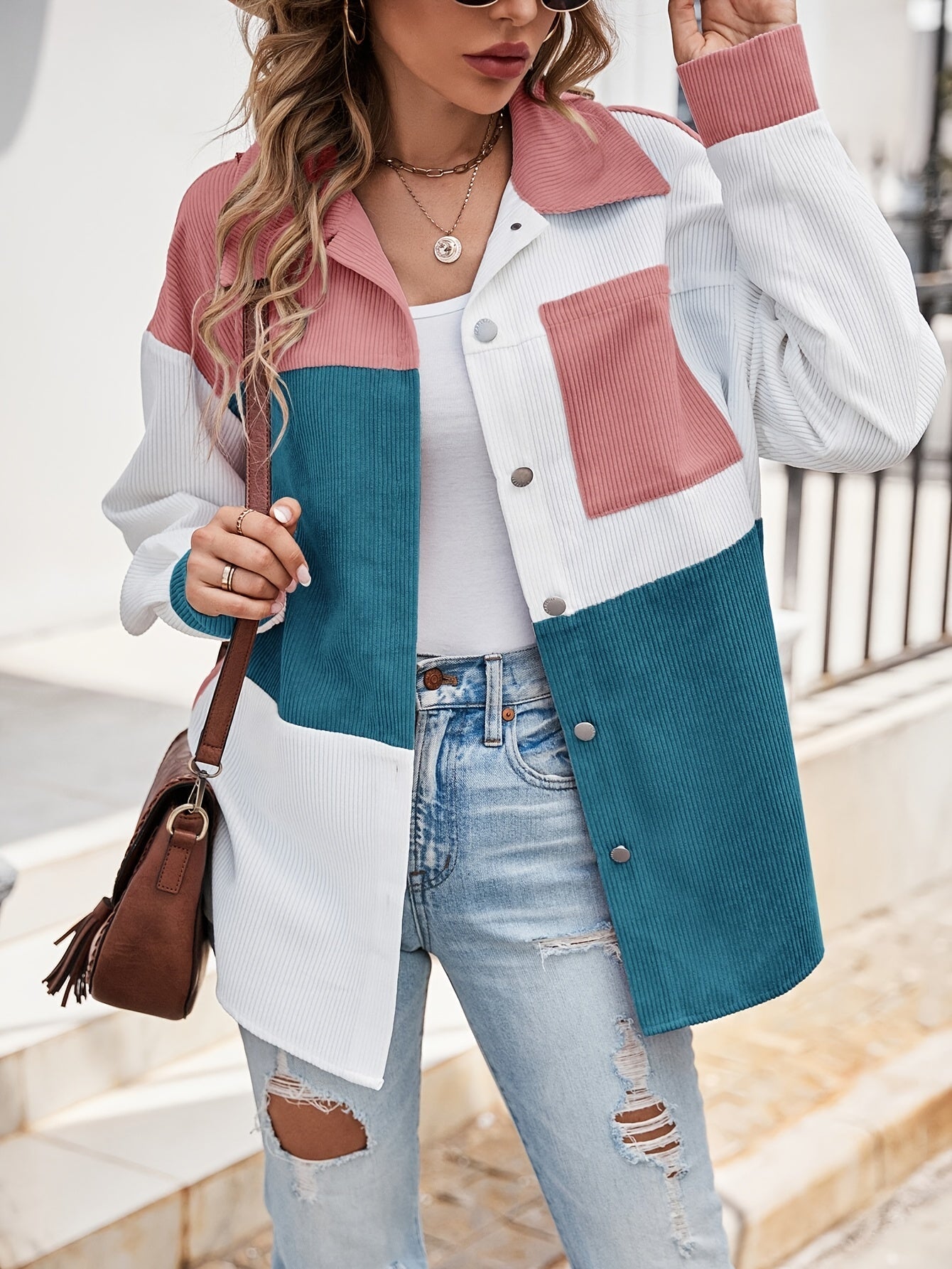 Frau in bunter Cordjacke, zerrissene Jeans, braune Tasche, modisch, urbaner Stil.