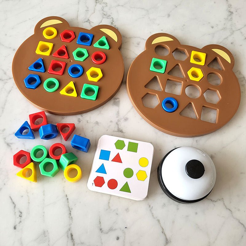 Braunes Bären-Form-Sortierspiel aus Kunststoff mit bunten geometrischen Formen auf Marmortisch.