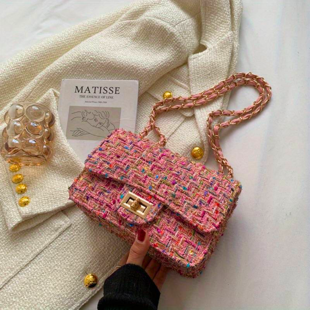 Bunte Tweed-Handtasche mit Kettengurt auf weißem Stoff, modisch, elegant, Damenaccessoire.