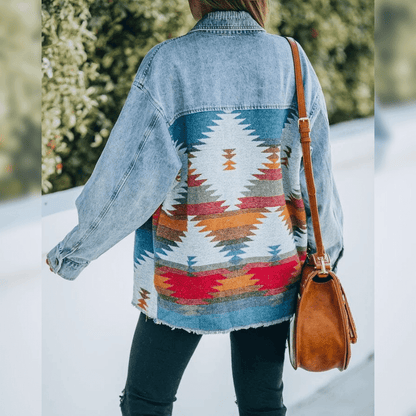 Frau in blauer Jeansjacke mit Ethno-Muster und brauner Ledertasche im Freien.