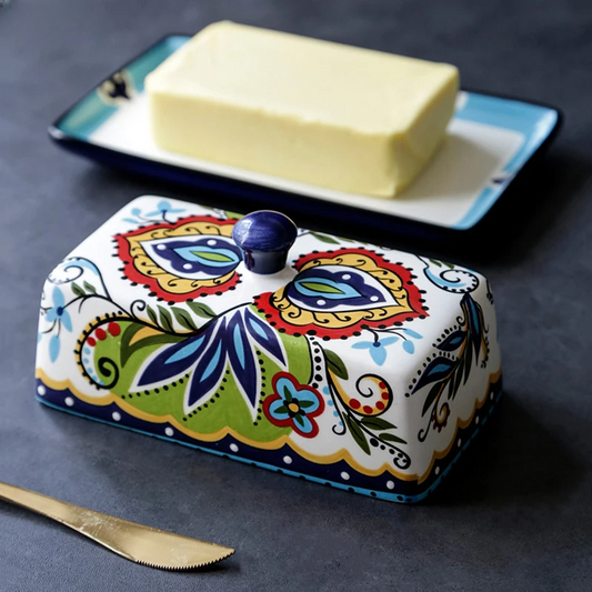 Bunte Keramik-Butterdose mit floralem Muster, rechteckig, auf dunklem Hintergrund.