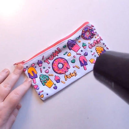 Bunte Kosmetiktasche mit Donut- und Eiscreme-Motiven, Reißverschluss, Hand hält Föhn.