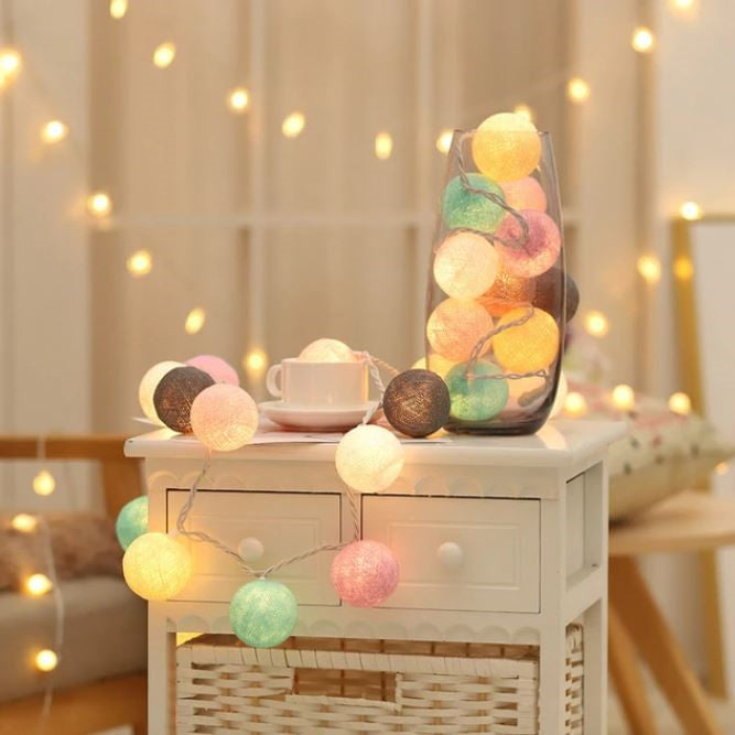 Bunte LED-Lichterkette in Glasvase auf weißem Tisch, dekorative Beleuchtung, gemütliches Ambiente.