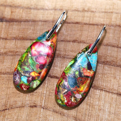 Bunte Harz-Ohrringe mit Silberhaken auf Holzoberfläche, handgefertigter Schmuck.