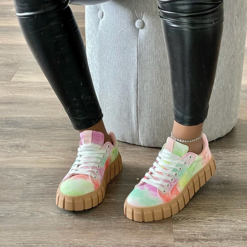 Farbige Damen-Sneaker mit dicker Sohle, Lederoptik, getragen auf Holzboden.