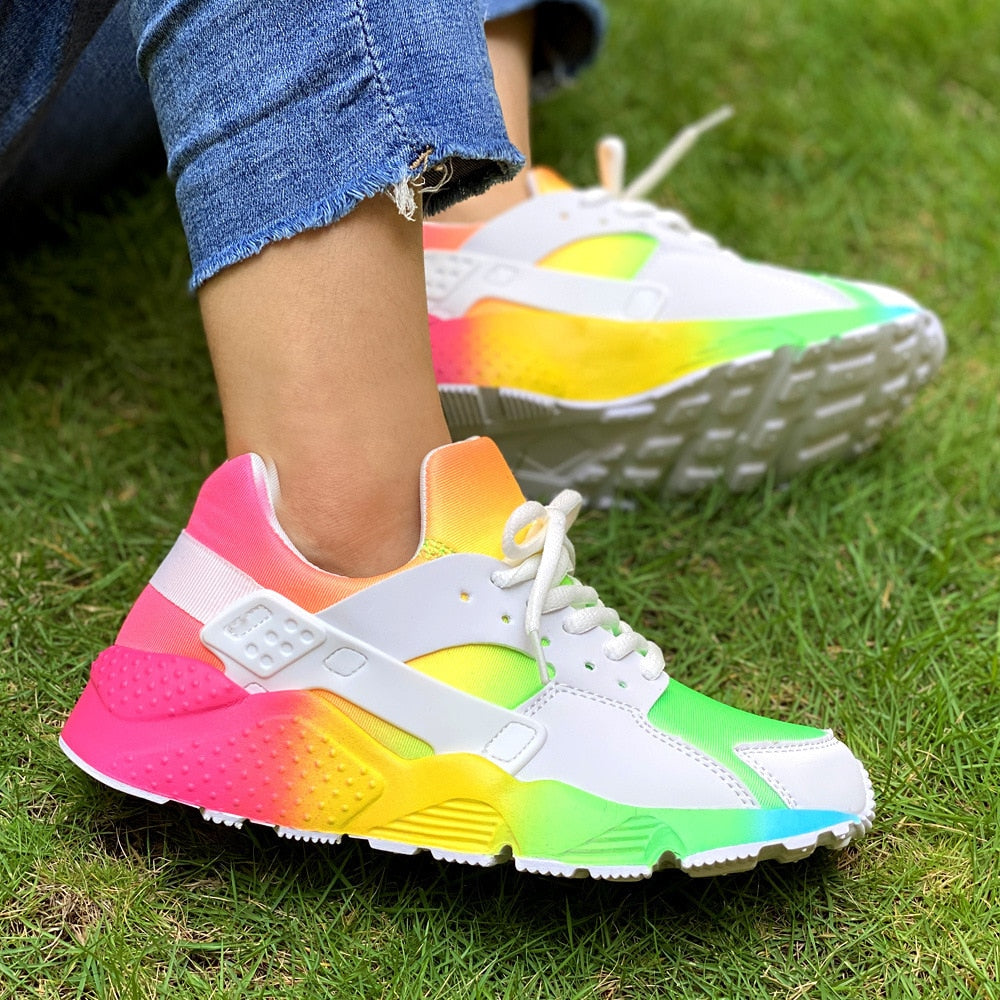 Weiße Sneaker mit buntem Farbverlauf, Damen, auf Gras, modisch, bequem, Freizeit.