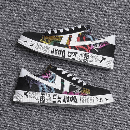 Schwarze Sneaker mit buntem Graffiti-Design und weißer Sohle auf grauem Hintergrund.