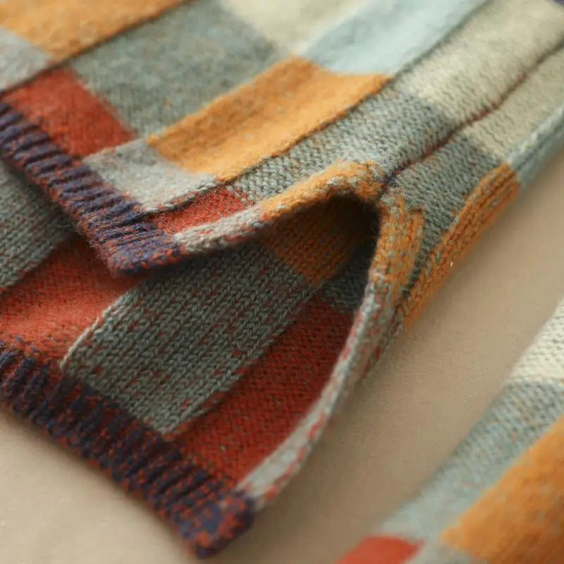 Bunte gestrickte Decke aus Wolle, kariertes Muster, warme Herbstfarben, gemütliches Wohnaccessoire.