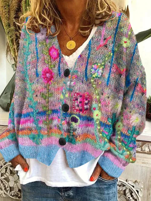 Frau trägt bunte Strickjacke mit Blumenmuster, V-Ausschnitt, Knöpfen, lässiger Stil.