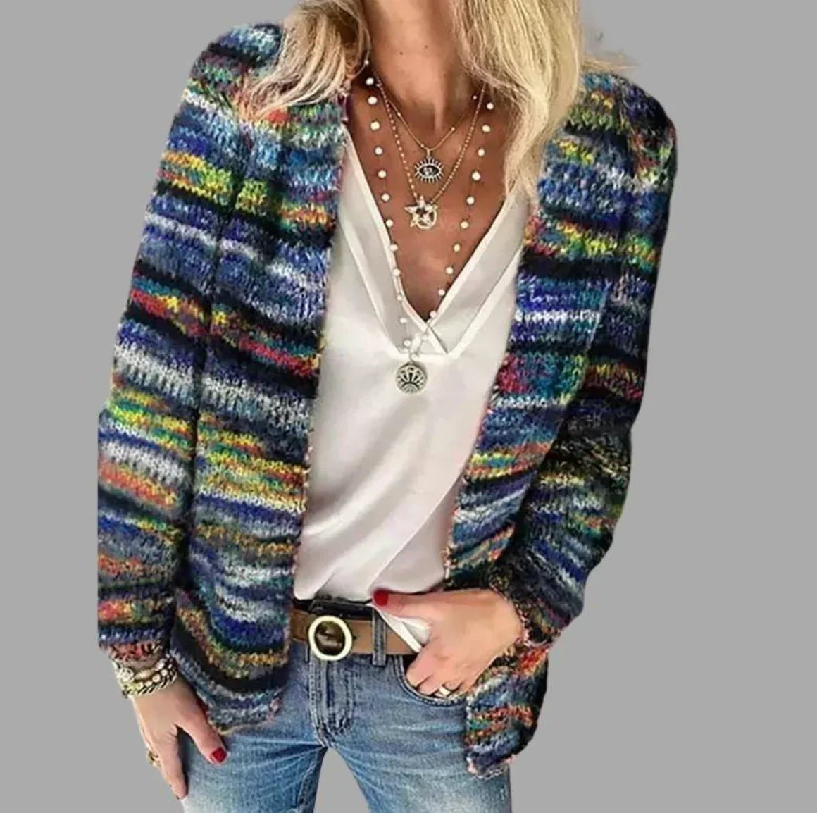 Frau in bunter Strickjacke, weißem Top, Jeans, Schmuck; modische Damenbekleidung.
