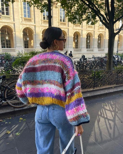 Frau in bunter Strickjacke und Jeans, spaziert in der Stadt, Herbstmode, lässiger Stil.