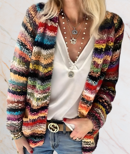 Frau mit buntem Strickcardigan, weißer Bluse, Jeans und Schmuck, modisch, lässig.