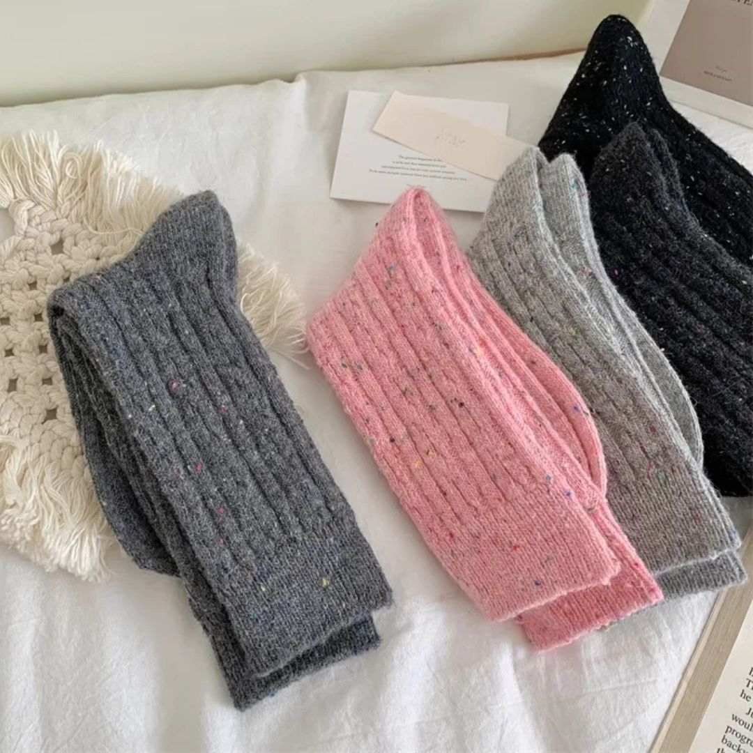 Bunte gestrickte Wollsocken, grau und rosa, auf weißem Hintergrund, gemütliche Wintermode.