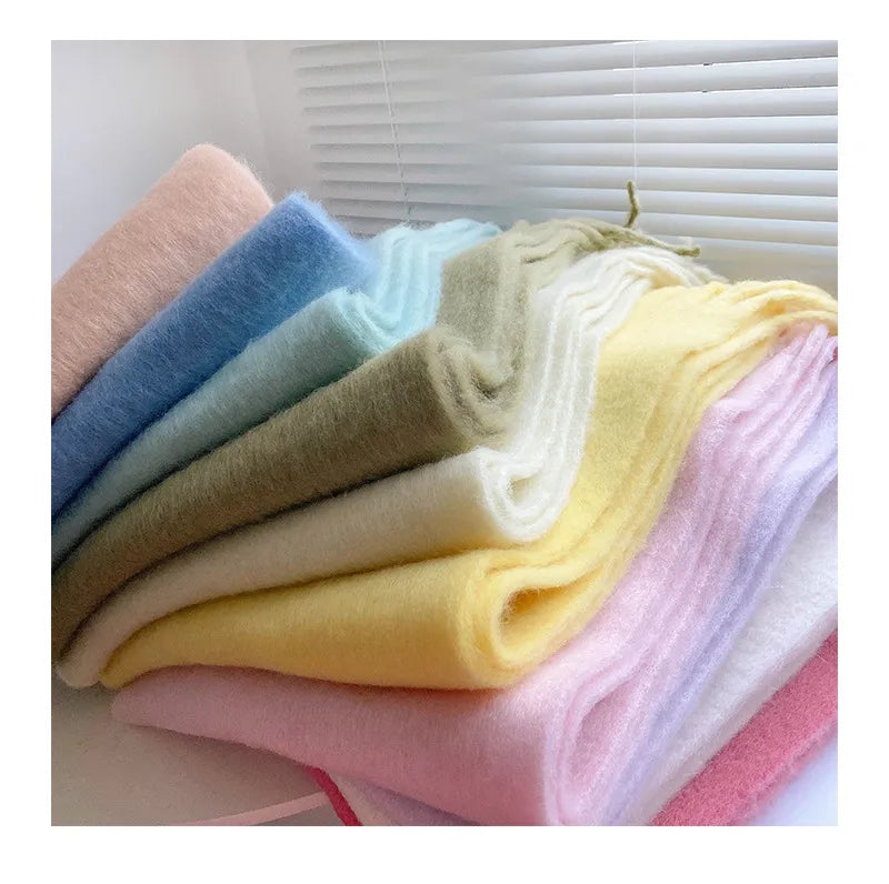 Mehrfarbige, weiche Wollschals aufgestapelt, Pastelltöne, gemütliche Winteraccessoires.