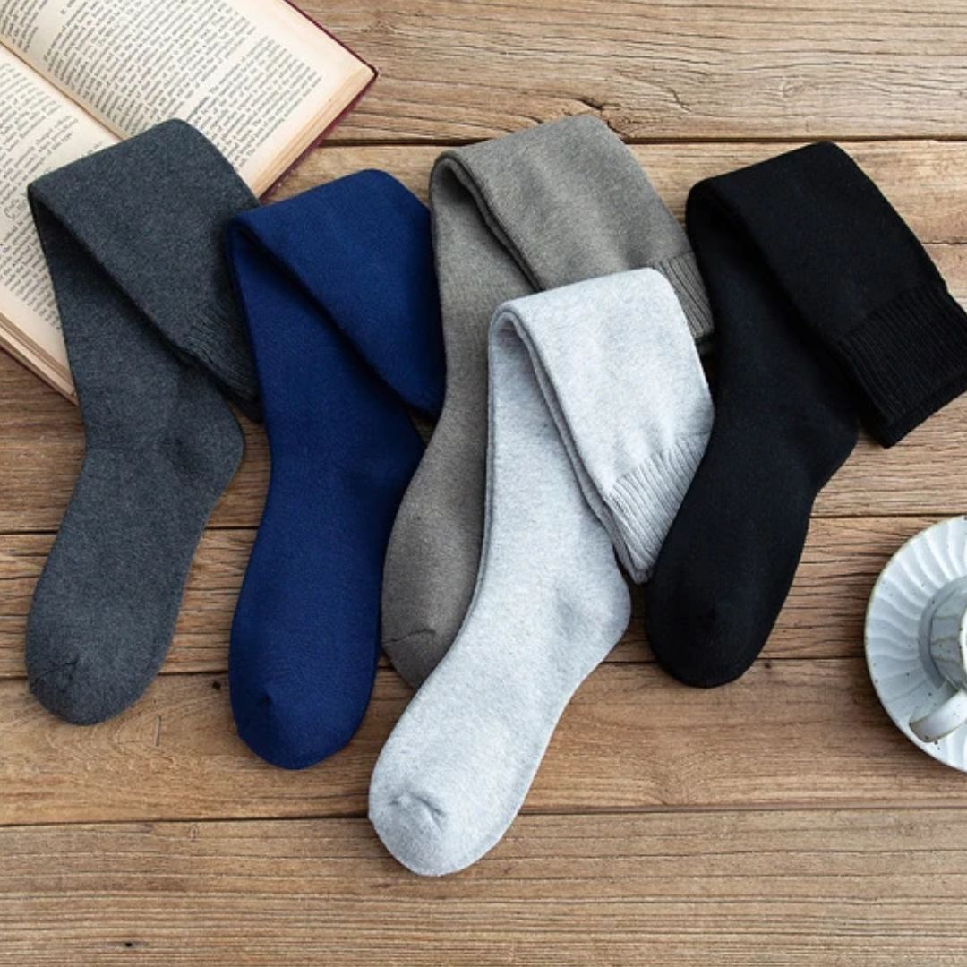 Fünf Paar bunte Baumwollsocken auf Holztisch, ideal für Herbstmode und Komfort.