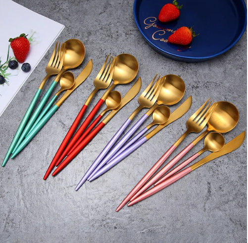 Buntes Besteckset aus Edelstahl, goldene Löffel, Gabeln, Messer, moderne Tischdekoration.