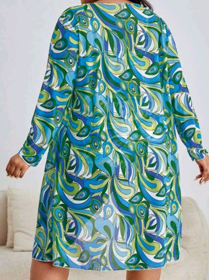 Frau in buntem, langärmligem Kleid mit blau-grünem Paisley-Muster, Rückansicht.