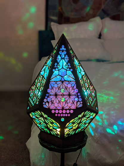 Buntes Tiffany-Lampe mit geometrischem Muster, beleuchtet, auf Nachttisch im Schlafzimmer.