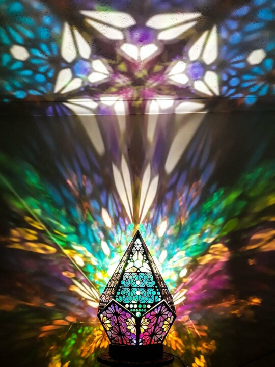 Buntes Tiffany-Lampe mit geometrischem Muster, projiziert farbenfrohe Lichtstrahlen an die Wand.